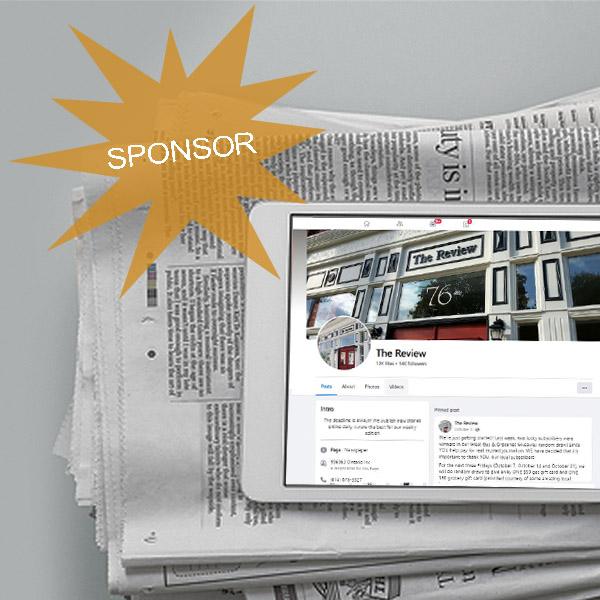 a newspaper on a counter with a tablet sitting on top of it displaying The Review Facebook page with a big gold star encouraging people to be a sponsor for one of The Review Facebook page contests