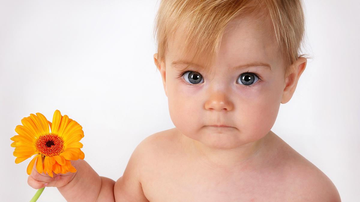 cute baby holding an orange flower in hand
