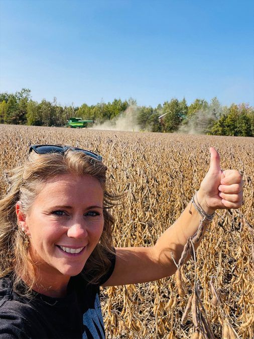 This is a photo of Sandra Clément in a cash crop field with a tractor.
